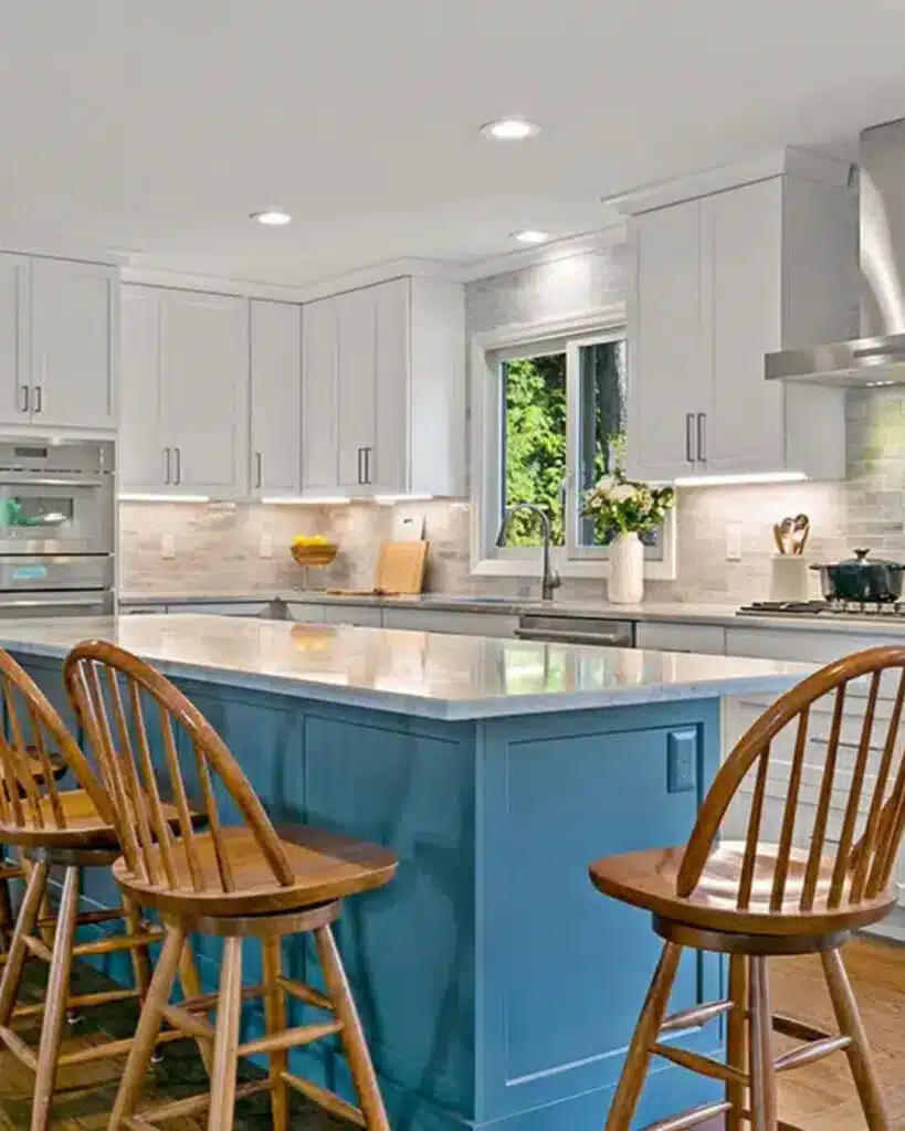 Large blue kitchen island with a marble countertop and wooden bar stools